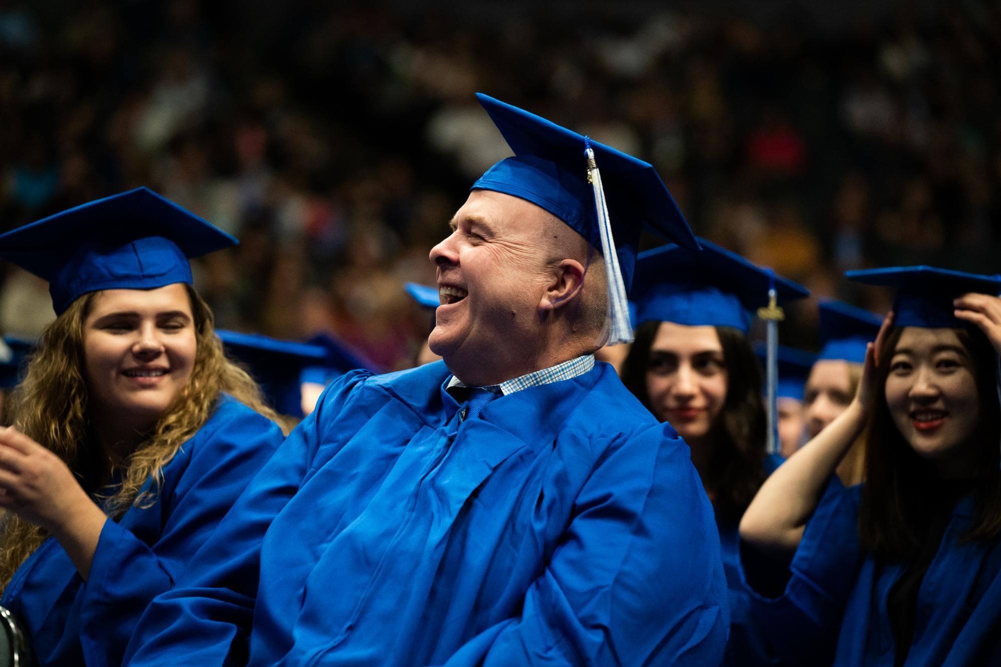 adult learner in blue graduation cap smiling